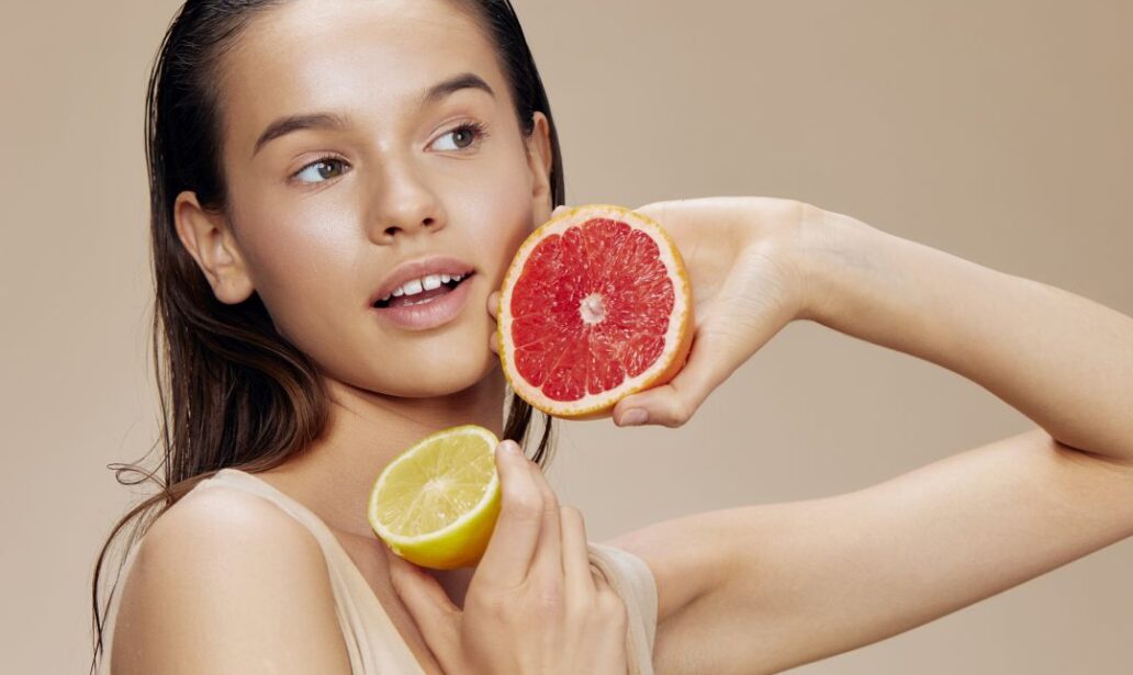 woman with glowing skin holding citrus fruits after antioxidant essence skincare routine